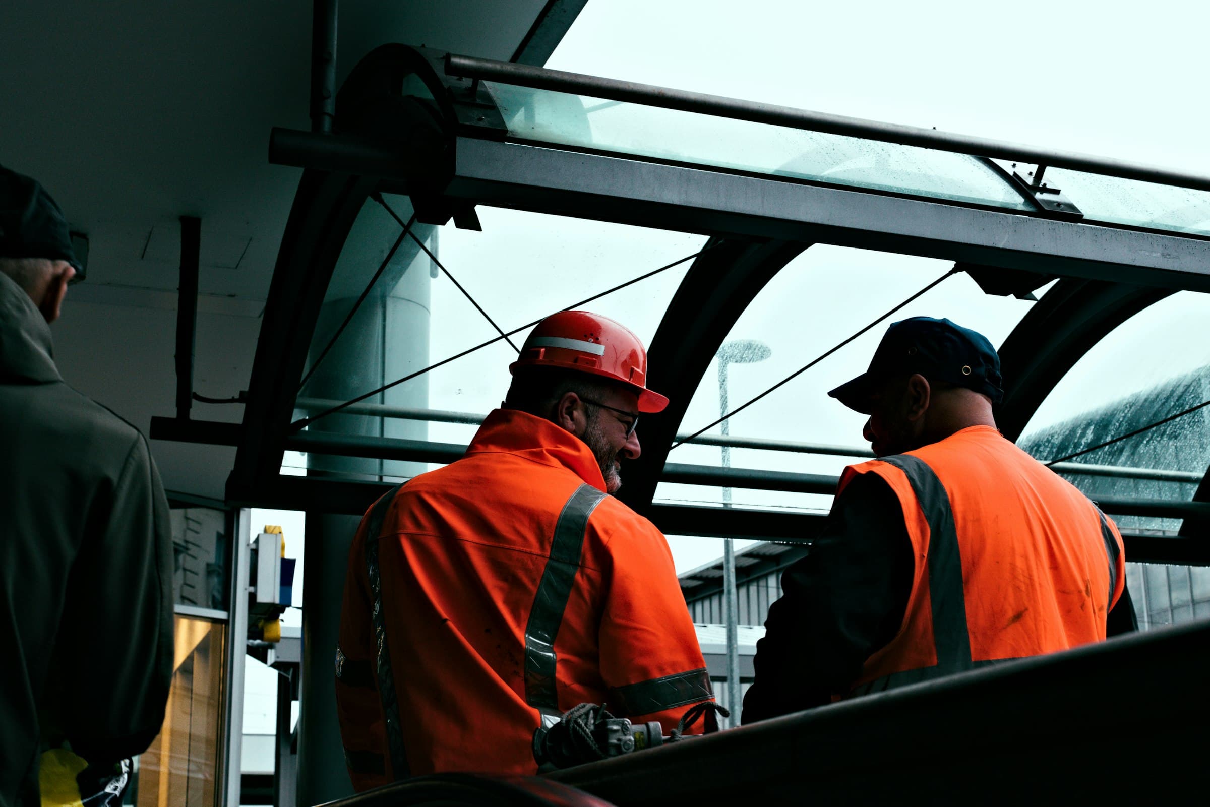 Twee medewerkers in oranje veiligheidskleding met helm aan het werk